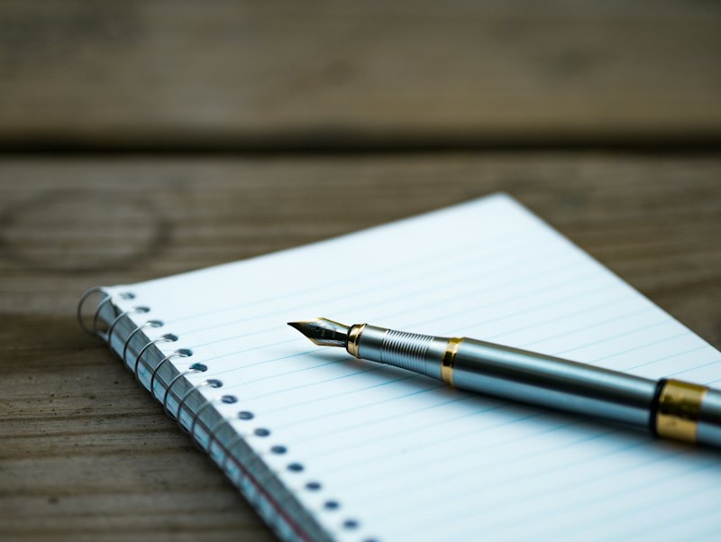 A fountain pen lying on a blank page of a spiral notebook