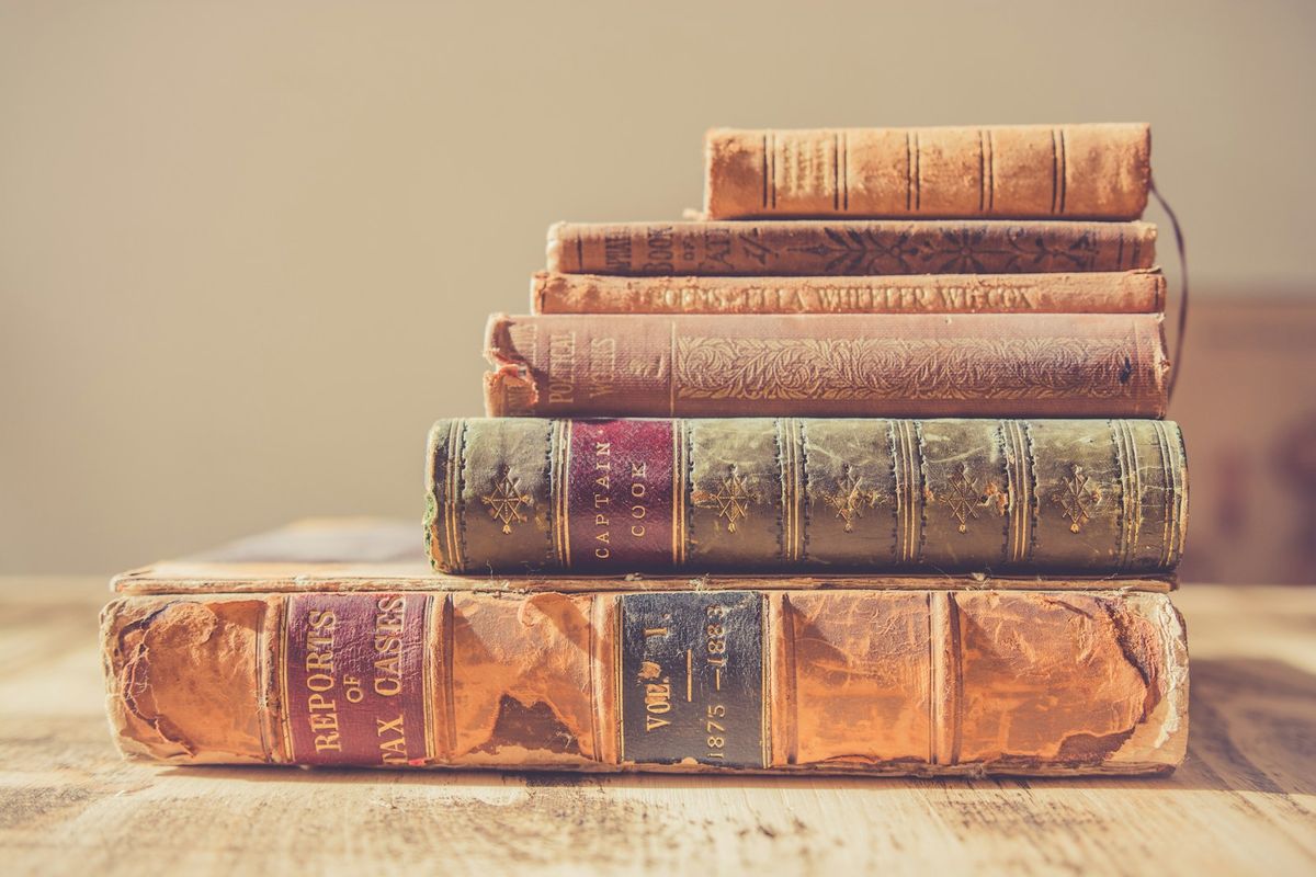 A stack of old leather-bound books on a wooden table